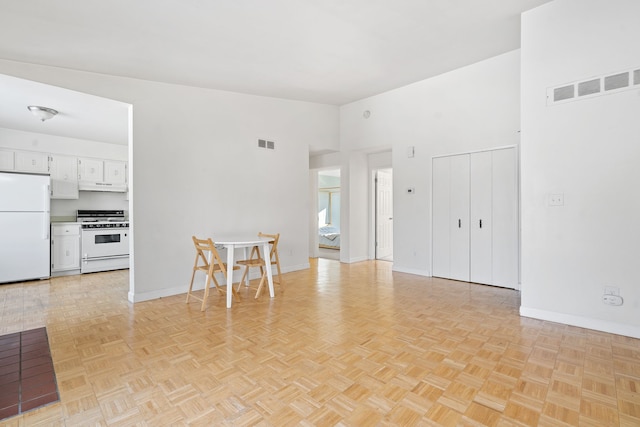 unfurnished living room featuring light parquet flooring and a high ceiling