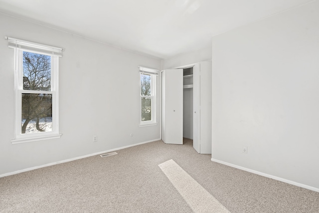 unfurnished bedroom with a closet and light colored carpet