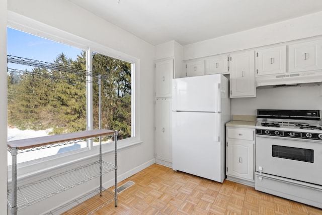 kitchen with white cabinets, white appliances, and light parquet floors