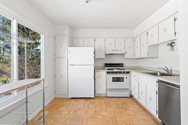 kitchen with sink, white appliances, white cabinets, and light parquet flooring