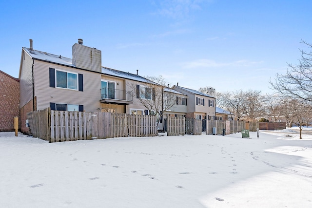 snow covered back of property with a balcony