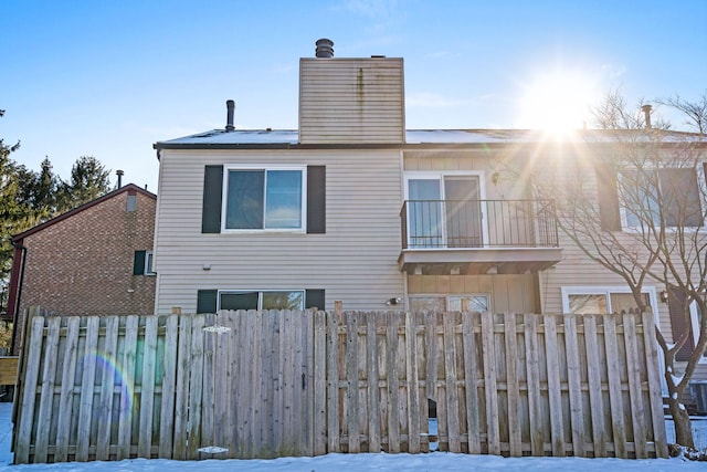 snow covered house featuring a balcony