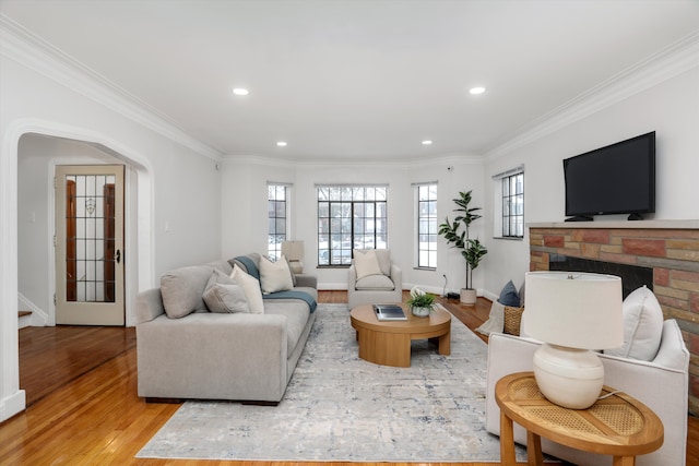 living room featuring a fireplace, crown molding, and light hardwood / wood-style floors