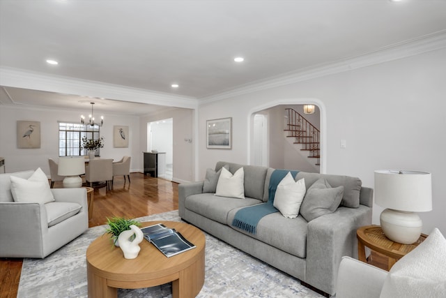 living room with light hardwood / wood-style floors, ornamental molding, and an inviting chandelier