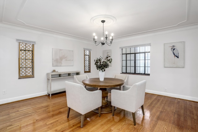 dining room with an inviting chandelier, crown molding, and light hardwood / wood-style floors