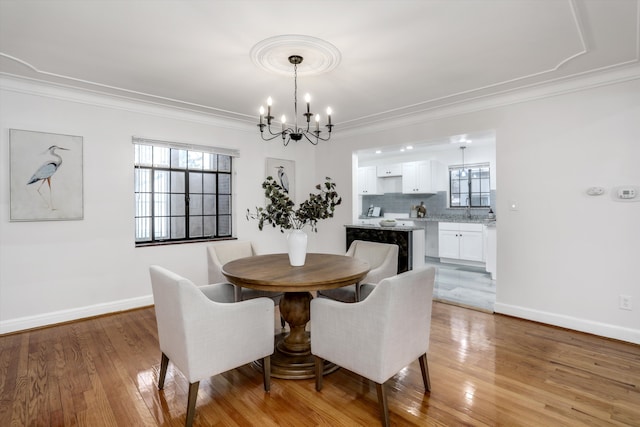 dining space with an inviting chandelier, ornamental molding, and light hardwood / wood-style flooring