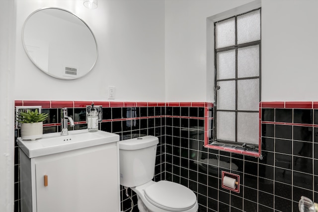 bathroom with toilet, tile walls, and vanity