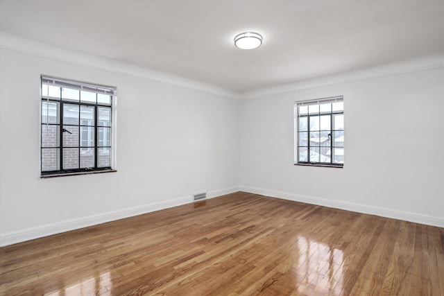 spare room featuring plenty of natural light, ornamental molding, and hardwood / wood-style flooring