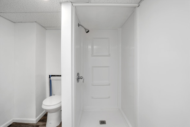 bathroom with toilet, a paneled ceiling, and a shower