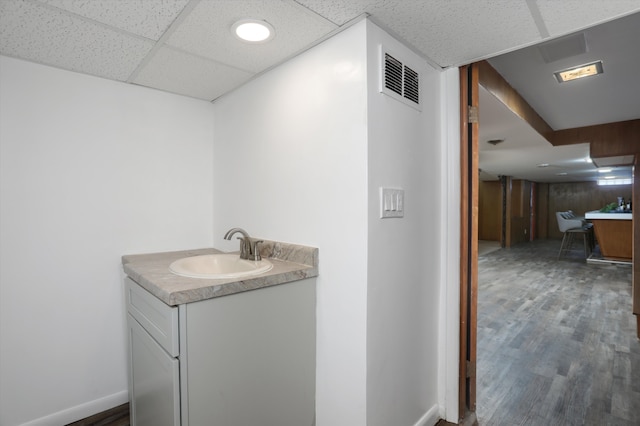 bathroom featuring hardwood / wood-style floors, a drop ceiling, and vanity