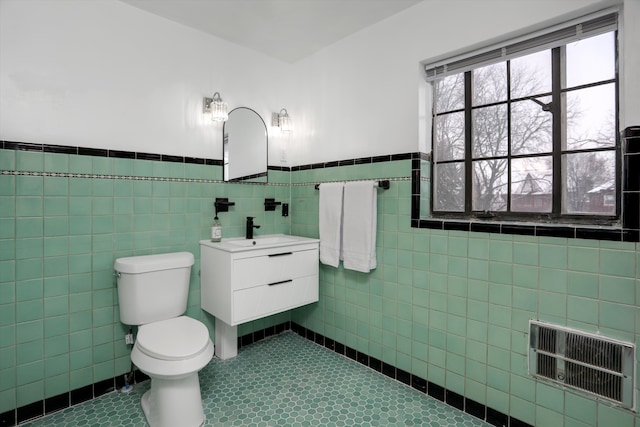 bathroom featuring tile patterned flooring, vanity, tile walls, toilet, and heating unit