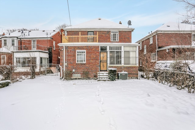 snow covered rear of property with cooling unit and a balcony