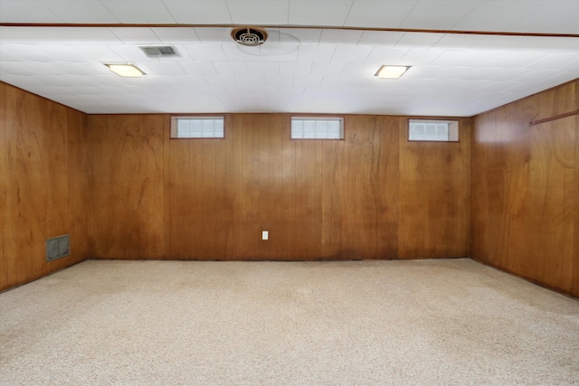 basement featuring light colored carpet and wooden walls