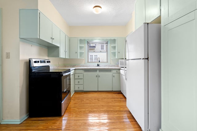 kitchen with sink, a textured ceiling, white appliances, and light hardwood / wood-style flooring