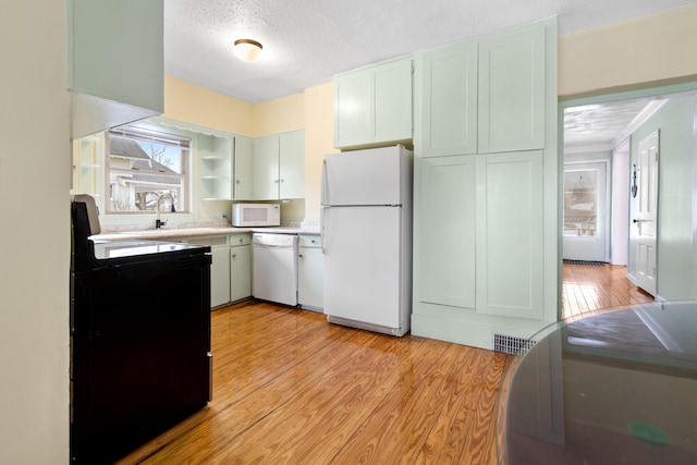 kitchen featuring sink, white appliances, a textured ceiling, and light wood-type flooring