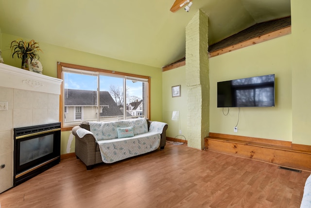 living room with a fireplace, vaulted ceiling, and wood-type flooring