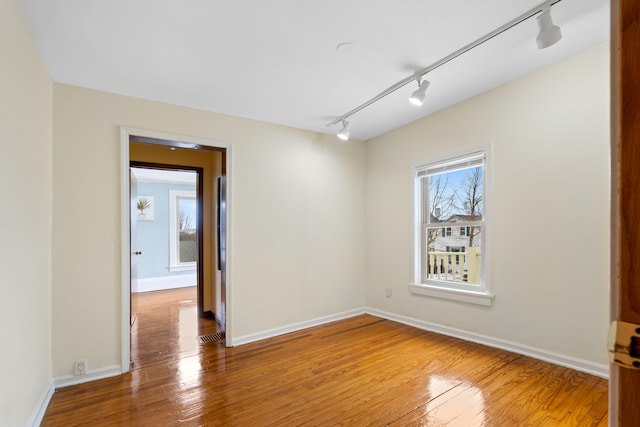 empty room with hardwood / wood-style floors and track lighting