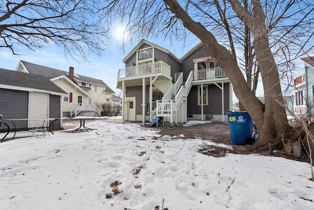 snow covered house featuring a balcony