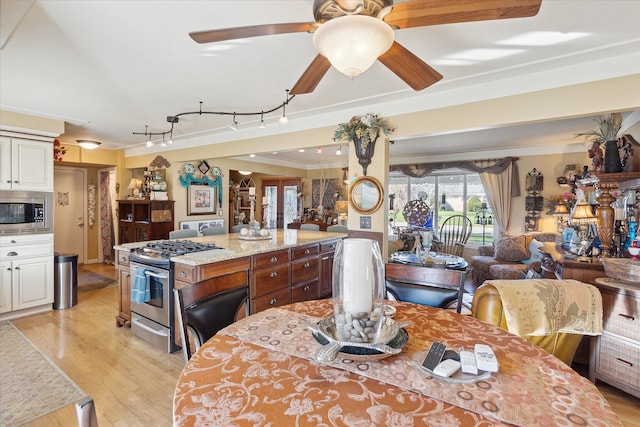 dining area featuring ceiling fan, ornamental molding, and light hardwood / wood-style flooring