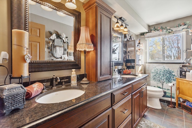 bathroom with toilet, vanity, and tile patterned flooring