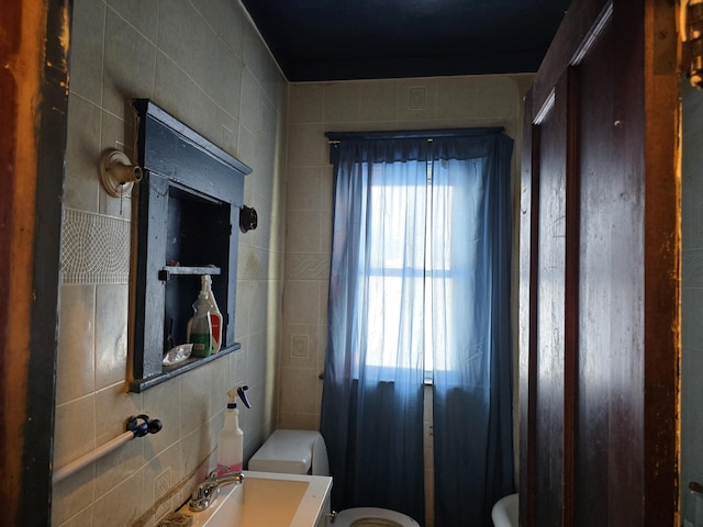 bathroom with tile walls, toilet, and vanity