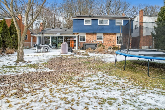 snow covered property featuring central AC, a trampoline, and solar panels