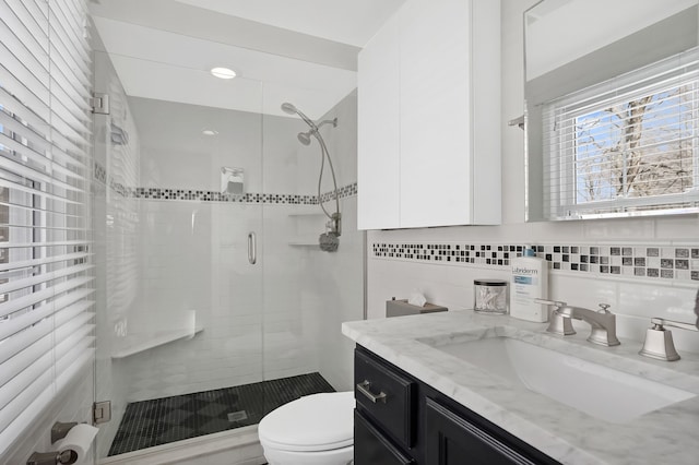 bathroom with vanity, backsplash, a shower with door, and toilet