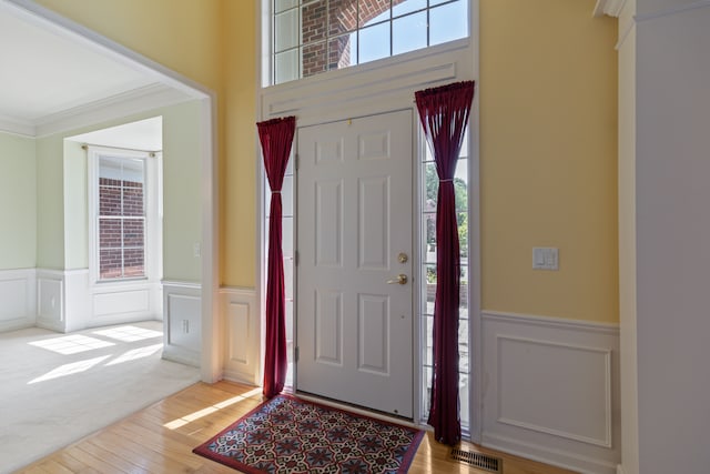 carpeted entrance foyer with crown molding