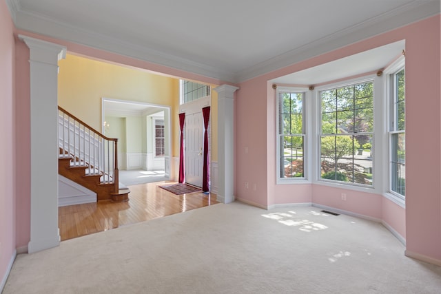 interior space featuring ornate columns, ornamental molding, and light colored carpet