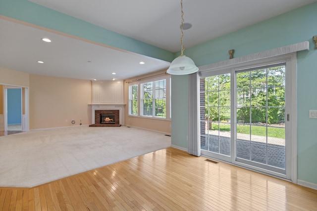 unfurnished living room featuring a brick fireplace and light hardwood / wood-style floors