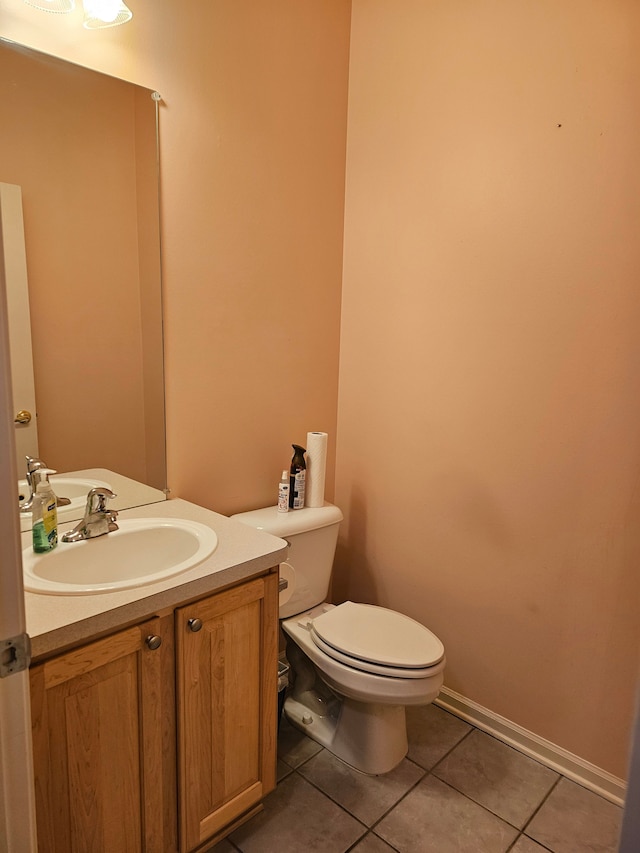 bathroom with toilet, vanity, and tile patterned flooring