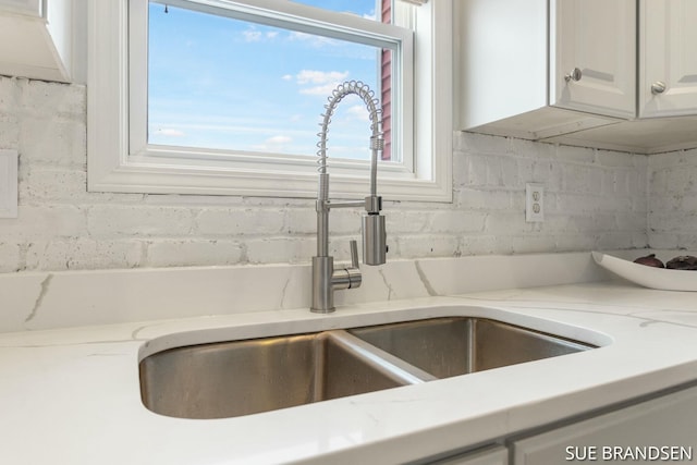 interior details with light stone countertops, white cabinets, and sink