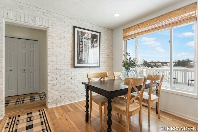 dining room with light hardwood / wood-style floors and brick wall