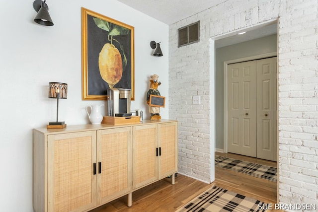 entryway with brick wall and light hardwood / wood-style floors