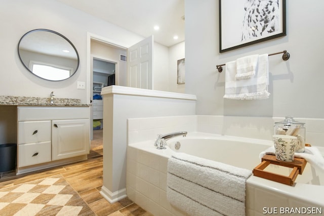 bathroom with tiled tub and vanity