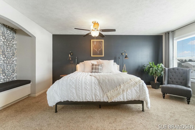 carpeted bedroom featuring ceiling fan and a textured ceiling