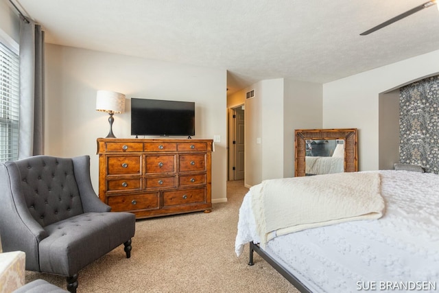 bedroom with light carpet, ceiling fan, and a textured ceiling