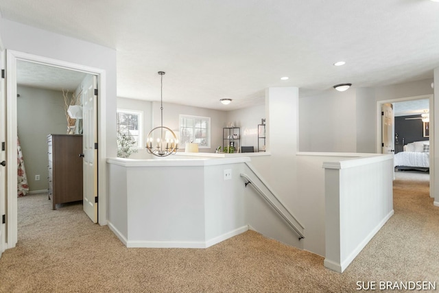 hallway with light colored carpet and an inviting chandelier