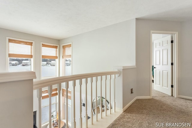 hallway with a textured ceiling and carpet flooring