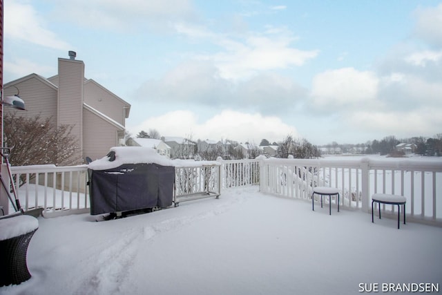 snow covered patio with a grill and a wooden deck