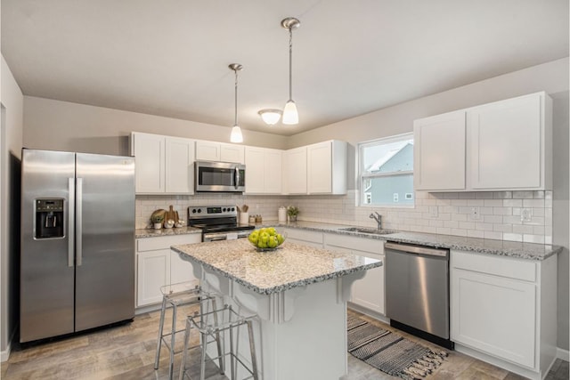 kitchen featuring white cabinets, decorative light fixtures, appliances with stainless steel finishes, and sink