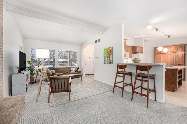 carpeted living room with sink, rail lighting, and lofted ceiling with beams