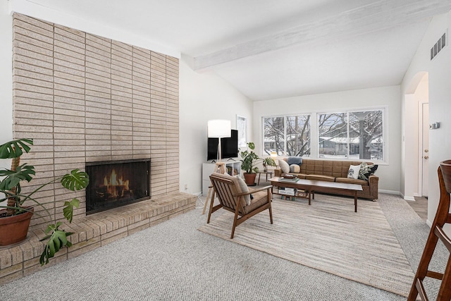 carpeted living room featuring a fireplace and vaulted ceiling with beams