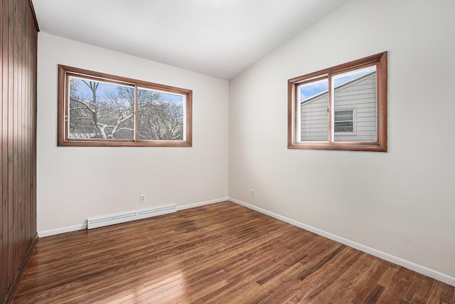 spare room featuring a baseboard heating unit, dark hardwood / wood-style flooring, and lofted ceiling