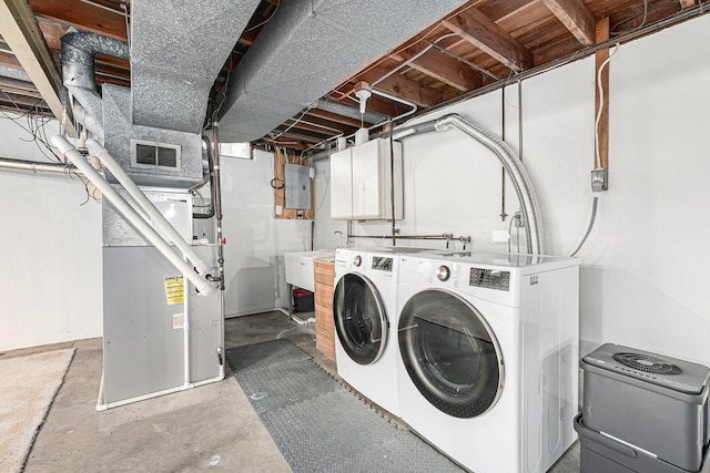 washroom featuring heating unit, washing machine and dryer, and sink