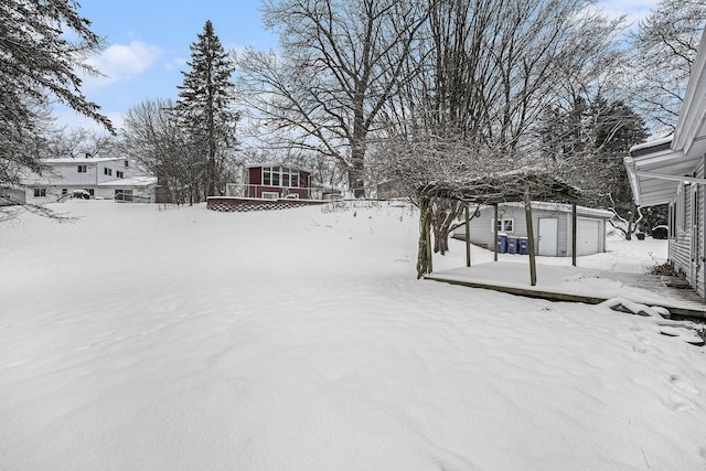 yard covered in snow with a garage and an outdoor structure