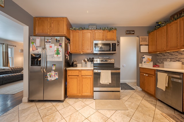 kitchen with light tile patterned floors, backsplash, and stainless steel appliances