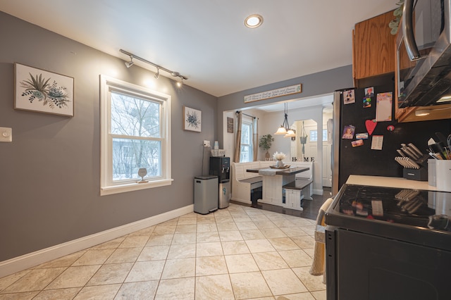 kitchen featuring light tile patterned floors, track lighting, stainless steel appliances, and pendant lighting