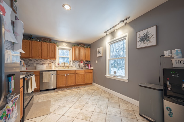 kitchen with backsplash, sink, track lighting, stainless steel appliances, and light tile patterned floors