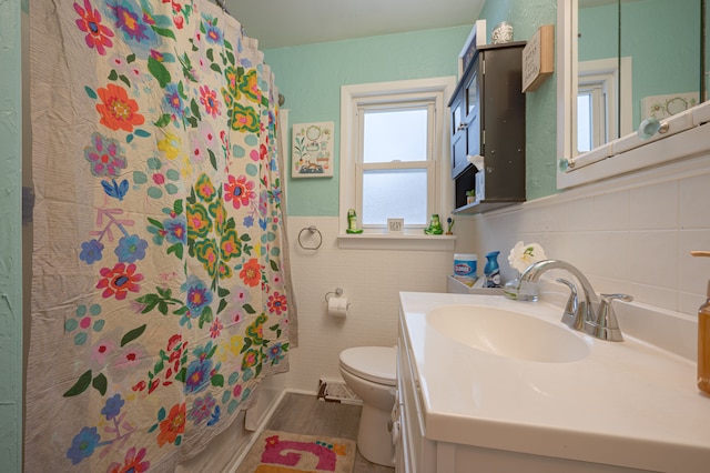 bathroom with toilet, vanity, and tile walls